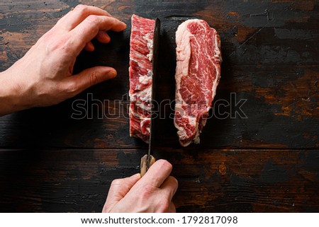 Raw Chuck eye roll black angus marbled beef steak on vintage dark wood table Organic beef. with butcher hands and meat cleaver at work chop Royalty-Free Stock Photo #1792817098
