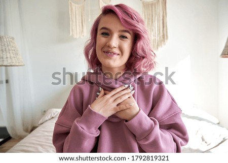 Happy hipster gen z teen girl blogger with smiling face with pink hair looking at camera recording live vlog channel, making video call, streaming on bed at home. Headshot portrait. Webcam view Royalty-Free Stock Photo #1792819321