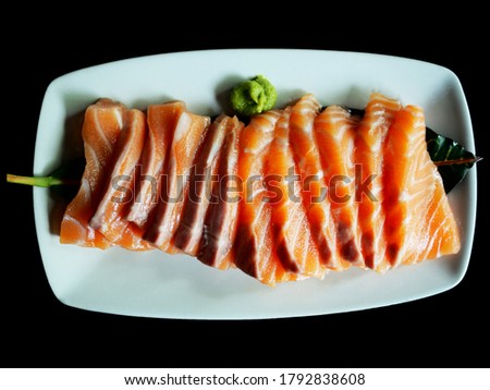 Top view picture of Salmon sashimi on white plate isolated on black background.