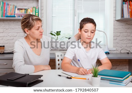 The tutor is engaged with the child, teaches to write and count. Mother helps son to do lessons. Home schooling, home lessons and distance learning. Quarantine and social distancing concept
