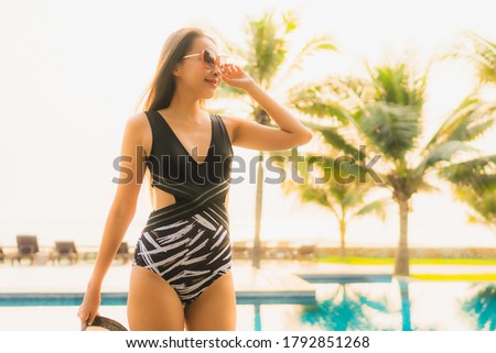 Portrait beautiful young asian woman relax around outdoor swimming pool in hotel resort with palm tree at sunset or sunrise for leisure vacation