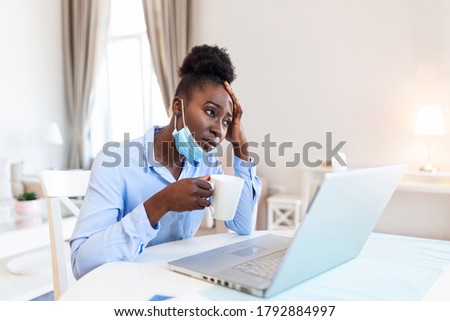 I can not believe I caught a cold! Frustrated african american businesswoman drinking hot beverage with protective mask. It's flu season. Sick young business woman at work