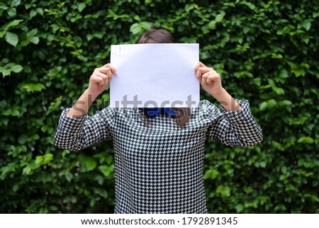 An Asian woman is standing with a white paper over her face. Able to put text for advertising media