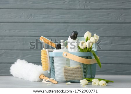 Set of cleaning supplies and spring flowers on grey wooden background Royalty-Free Stock Photo #1792900771