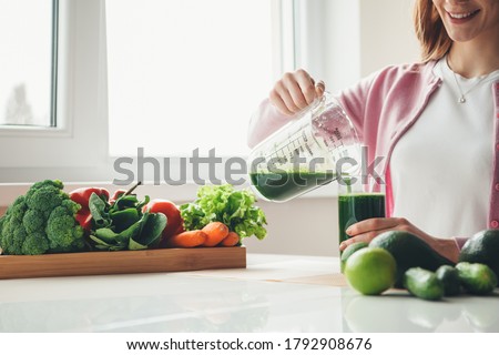 Toothily smiling red haired girl with freckles putting some vegetable juice in the glass Royalty-Free Stock Photo #1792908676