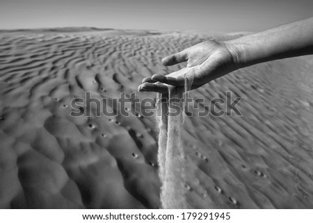 Sand slipping through the fingers of a woman's hand in the desert of Sahara in Tunisia.