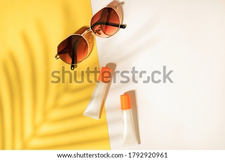 Sunscreen tube with sunglasses on tropical leaf shadow background . Skincare for summer and travel. Royalty-Free Stock Photo #1792920961