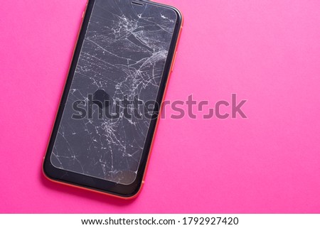 Broken glass mobile phone screen on a pink background