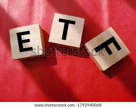 ETF, Exchange Traded Fund, realtime mutual index fund that can trade in equity stock market, cube wooden block with alphabet building the word ETF over red background. 

