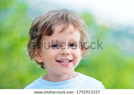 Emotional kid walks outdoors and enjoy walking. Portrait of a boy smiling. Has happy. Funny boy. Happy toddler boy in the park. Little cute kid is smiling. Emotions on the face. Copy space