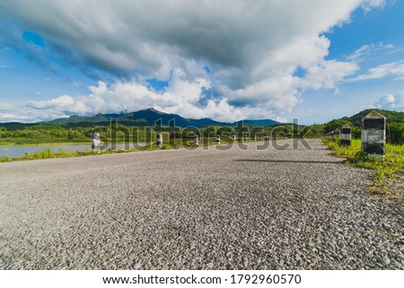 Black and white milestones on roadside with mountain and cloud
