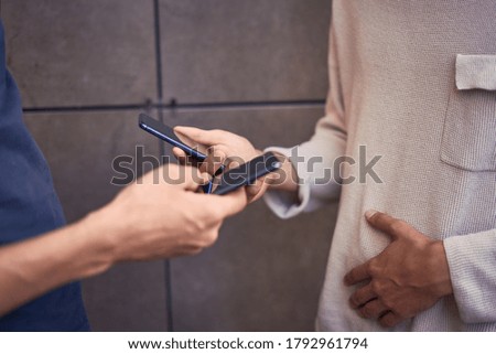 People with phones in their hands standing against  wall