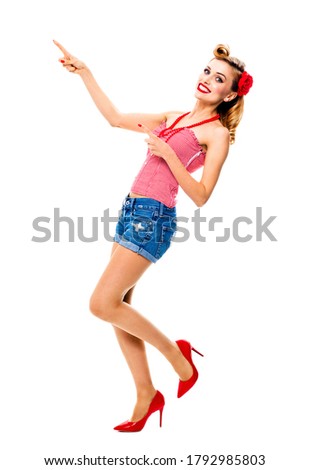 Full body portrait image - amazed happy woman pointing at something. Excited girl in pin up style, showing copy space for some text or imaginary. Retro fashion and vintage. Isolated over white. 