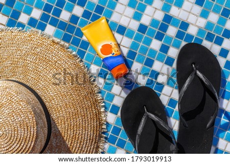 straw hat rubber flip flops sunscreen for body and face by the pool macro photo