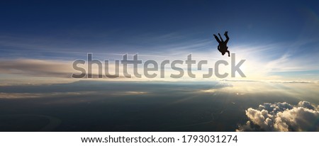 Tandam skydiving banner. Background of the sun and clouds in free fall.Man conquers the sky and flies upside down.Aerodynamics. 4000 meters above the ground. Extreme tourism.National airborne day Royalty-Free Stock Photo #1793031274