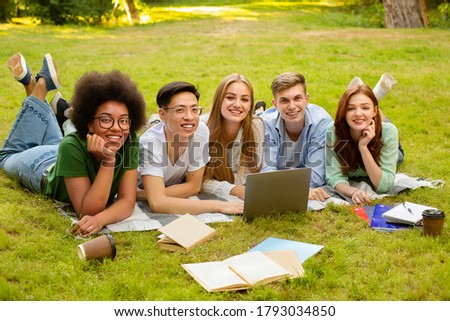 Students Life. Outdoor Portrait Of College Friends Preparing For Exam Together With Laptop And Workbooks, Lying on Lawn At Campus Royalty-Free Stock Photo #1793034850