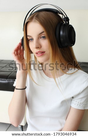 Beautiful young girl with blond hair listening to music on headphones