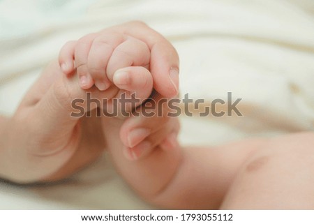 The hand of newborn baby holding the finger and hand of the mother