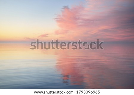 Baltic sea after the rain at sunset. Dramatic sky with glowing  pink clouds, symmetry reflections in the water. Abstract natural pattern, texture, background, concept art Royalty-Free Stock Photo #1793096965