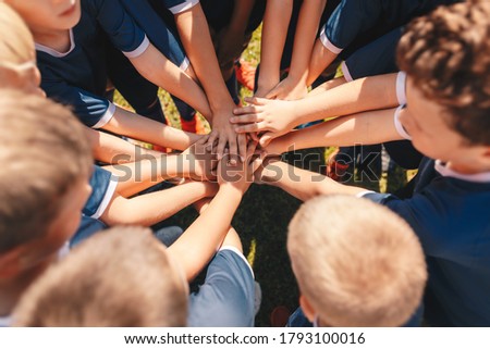 Happy kids sports team stacking hands at the field. Children team sports. Boys at sports camp stacking hands before a match. School age children in a team  Royalty-Free Stock Photo #1793100016