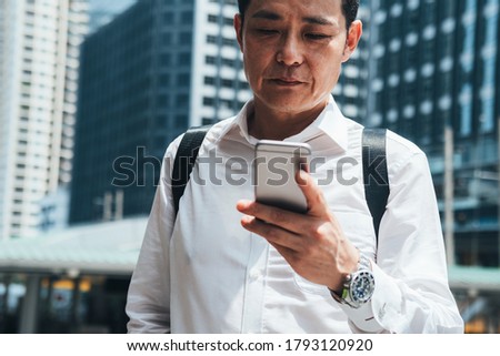 Business man holding phone in city outdoor with office building in the background stock photo