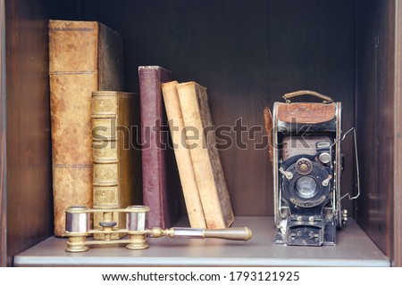 Old books and a camera on a vintage shelf in the closet, close-up