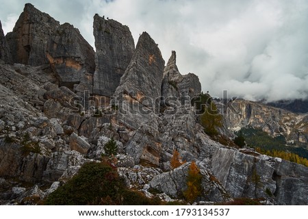 Rugged and rocky alpine mountain ranges with cloudy blue sky above in The Dolomites. These iconic mountain peaks are located at Cinque Torri in the Tyrol region of Italy. Royalty-Free Stock Photo #1793134537