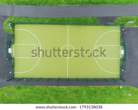 Aerial drone view on a basketball field. Nobody, Green court surface matches grass in a field.