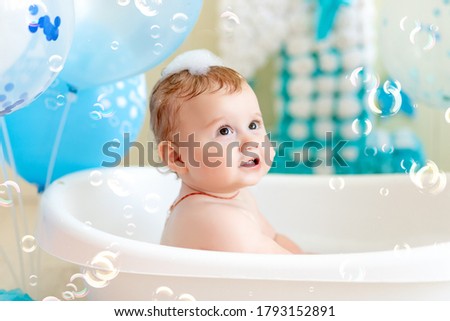 baby boy celebrates birthday 1 year in a bath with balloons, bathing baby with blue balloons