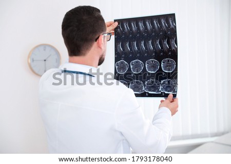 Professional orthopedist examining X-ray picture in clinic