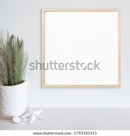 Wood frame mockup on white wall with beach/ocean theme decoration on white surface. Light wood. Copy space.