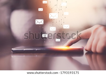 Woman hand using smart phone at coffee shop with email icon flying abstract background. Technology business and freelance concept. Vintage tone filter effect color style.