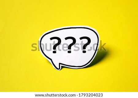 Three question mark speech bubble on white paper isolated on yellow paper background with drop shadow.