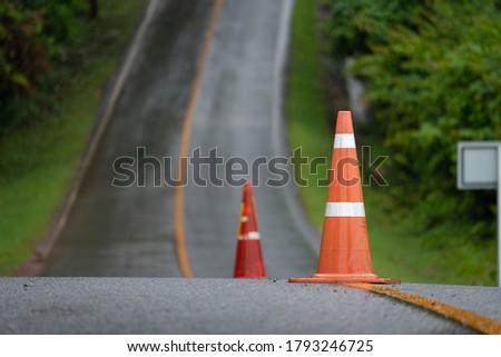 Traffic cone which is placed on the center line of asphalt road, using as safety sign for vehicle transportation.  Travel and journey concept background.