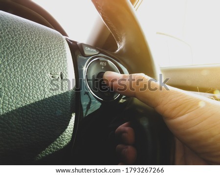 Driver pressing cruise control button switch on steering wheel of a car                       Royalty-Free Stock Photo #1793267266