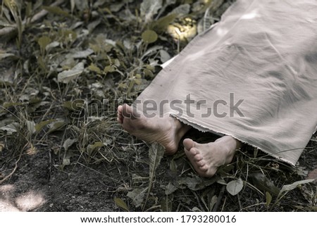 The legs of a corpse lying in the forest. The body of the victim of a crime. Deceased person.