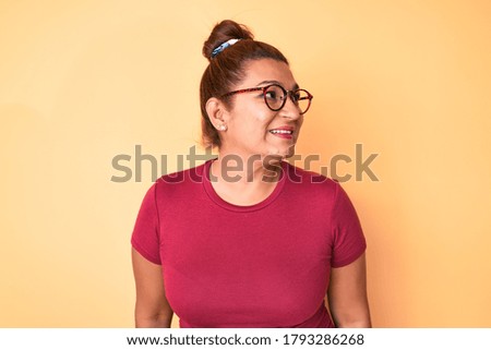 Middle age brunette hispanic woman wearing casual clothes and glasses looking to side, relax profile pose with natural face and confident smile. 