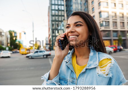 Cheerful young woman making a phone call outdoors in the city