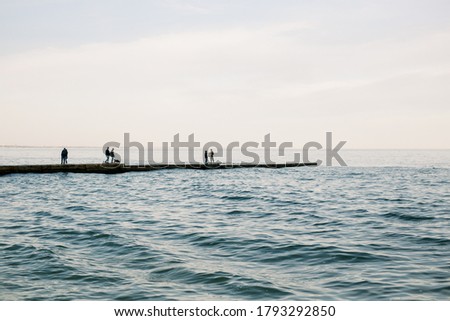 The sea is blue. The berth leads to the sea. People can be seen on the pier from afar. Free space. The photo is color. horizontal.