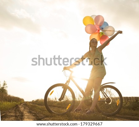  riding bicycle flying air balloons on leash yellow sun set sky background 