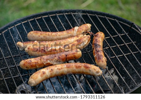 Delicious sausages frying on a grill outdoors.