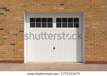 Classic look, white side hinged garage doors, on a new build home.  UK Royalty-Free Stock Photo #1793313679