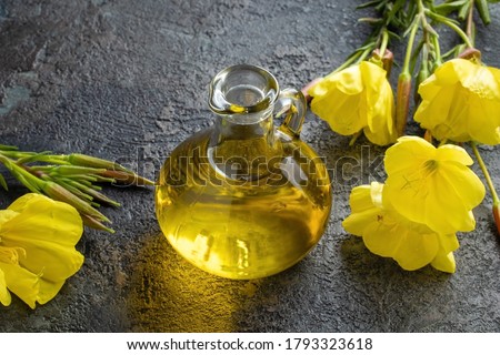A bottle of evening primrose oil with fresh blooming plant on a dark background Royalty-Free Stock Photo #1793323618