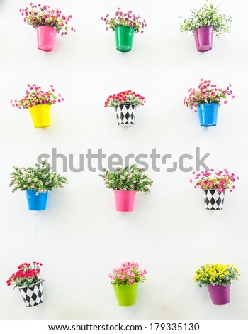 Plastic flower in vase on wall background