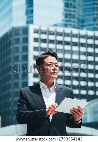 Business man using tablet in city outdoor with office building in the background stock photo