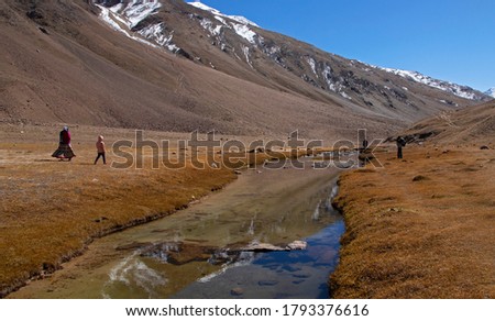 Tourists enjoy the scenic beauty of a clear stream and reflections on it. This picture was taken near Chandratal on a clear day.