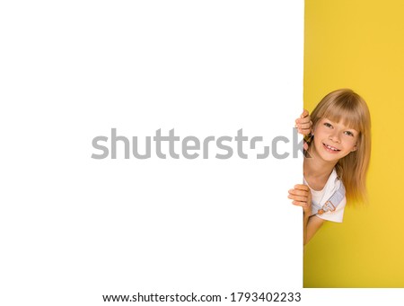 the kid blonde girl of school age 8-9 years old next to a white blank for text or image on yellow background. Advertising Banner for a website, social networks, Billboard