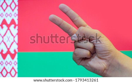 a sign of victory on the background of the Belarusian flag