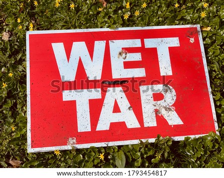 Wet tar sign on ground, red and green
