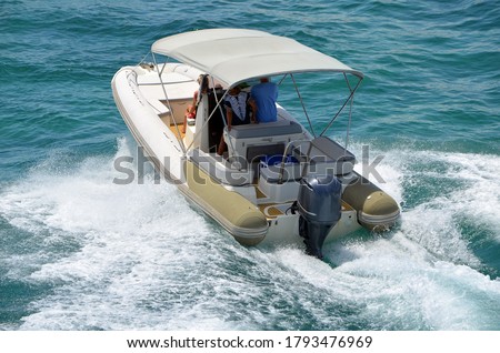 Angled elevated view of a pontoon motor boat with a Bimini top. Royalty-Free Stock Photo #1793476969